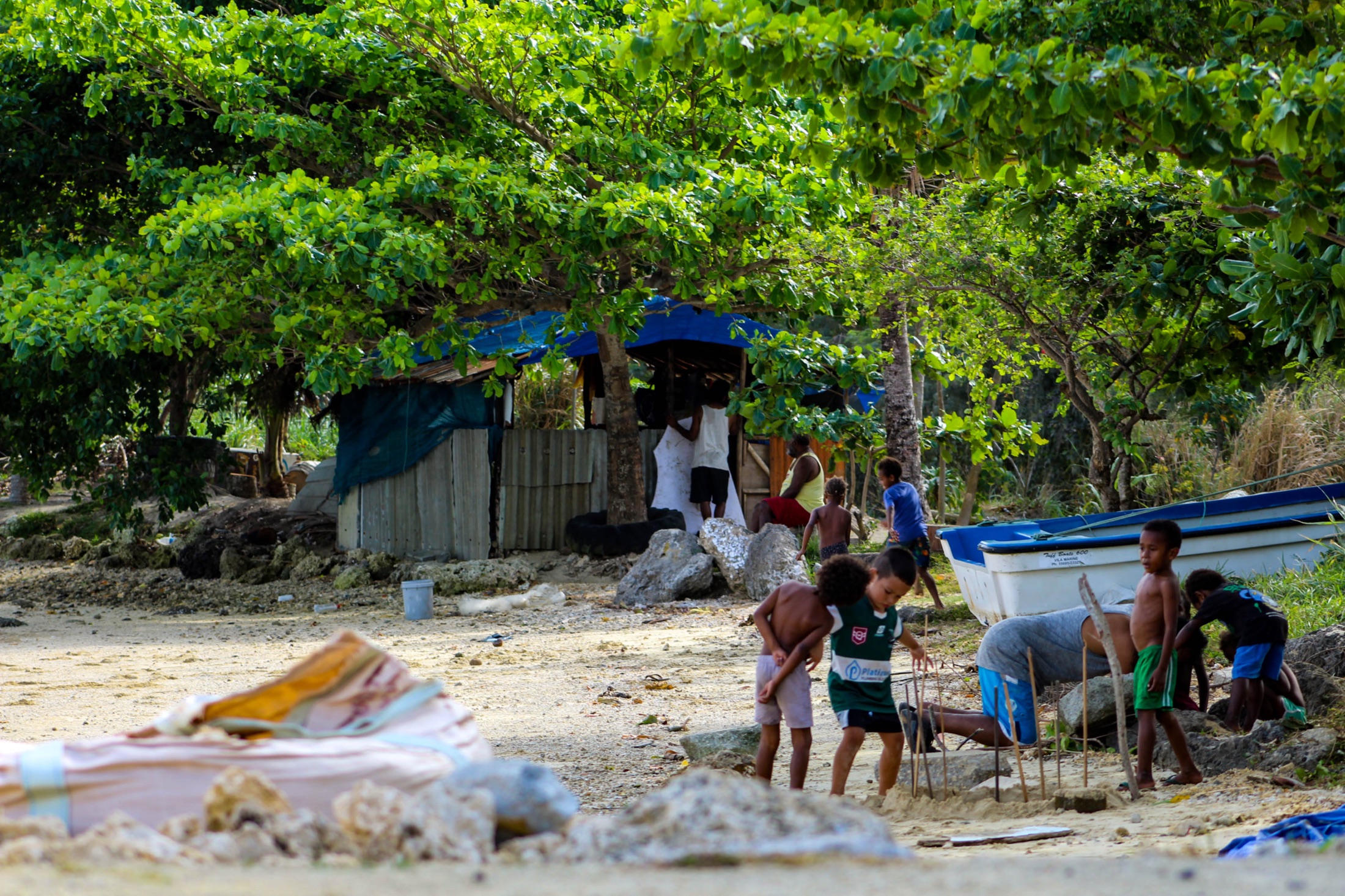 Local families spending time beside the water under tropical trees.